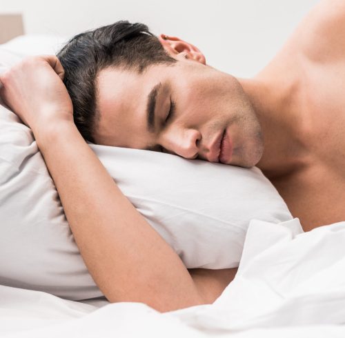 handsome and muscular man lying on bed with closed eyes